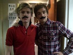 two men with fake moustaches on their faces posing for a photo together