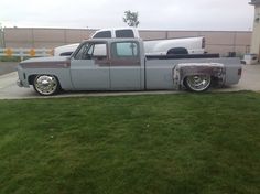 an old pickup truck with chrome rims parked on the side of a road in front of a building