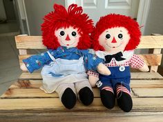 two red haired dolls sitting on a wooden bench