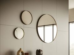 three circular mirrors mounted on the wall above a table with vases and other items