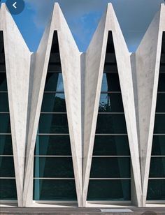 the building is made of concrete and has triangular shaped windows on each side, along with glass doors