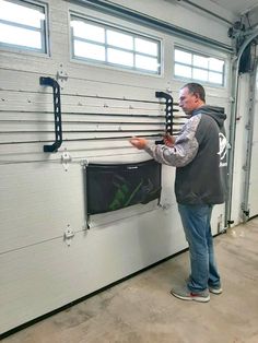 a man standing in front of a garage door looking at a screen on the wall