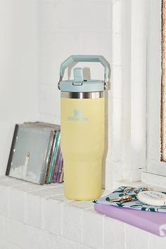 a yellow water bottle sitting on top of a window sill next to a book