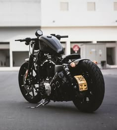 a black motorcycle parked on the street in front of a building with no one around it