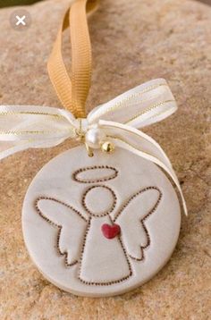 a white ornament with an angel design on it's side hanging from a yellow ribbon