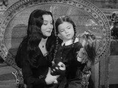 an old black and white photo of two women sitting on a chair with a cat