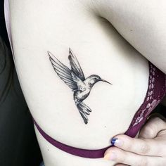 a woman's stomach with a small tattoo of a hummingbird on her side