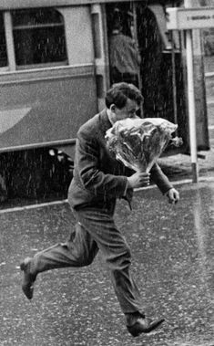 a man is running in the rain with an umbrella over his head while carrying something