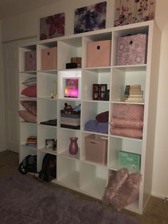 a white book shelf filled with lots of pink and purple items on top of it