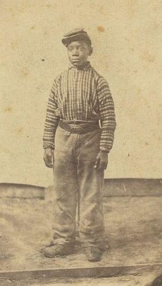 an old black and white photo of a young boy wearing a hat standing on a platform