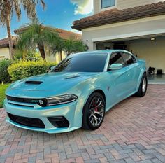 a light blue car parked in front of a house with palm trees on the driveway