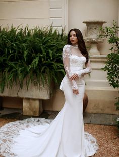 a woman in a white wedding dress standing next to plants and potted planters