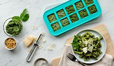 a plate of pasta with pesto on it next to other ingredients and utensils