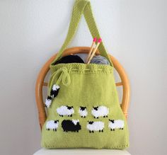 a green bag with black and white sheep on it sitting on top of a chair