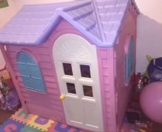 there is a pink toy house with blue doors and windows on the floor next to a balloon