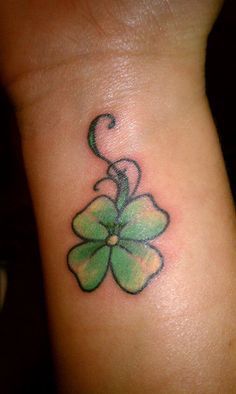 a green four leaf clover tattoo on the wrist