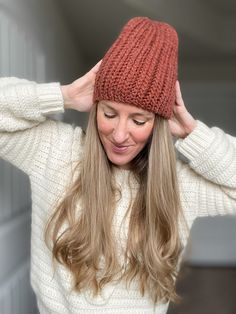 a woman with long hair wearing a red knitted hat and looking at the camera