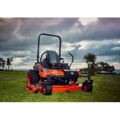 an orange riding mower sitting on top of a lush green field