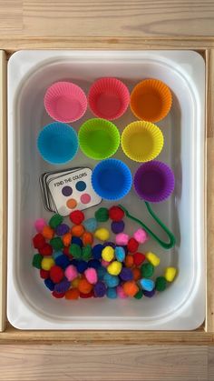 the tray is filled with colorful cupcake liners and pom - poms