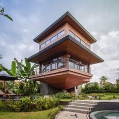 a tall wooden building sitting in the middle of a lush green field next to trees