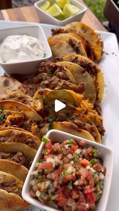 mexican food is served on a white platter with bowls of salsa and tortillas