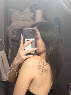 a woman taking a selfie in front of a mirror with a flower tattoo on her back