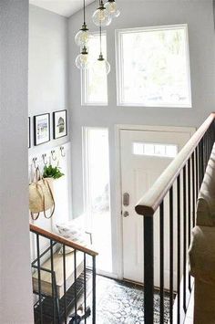 an entryway with stairs and pictures on the wall above it, along with hanging baskets