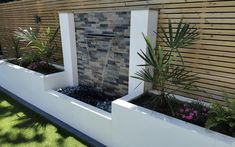 a water feature in the middle of a garden with flowers and plants growing around it