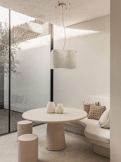 a white table and some chairs in a room with glass walls on one side and floor to the other