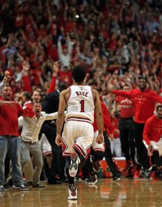 a basketball player is walking on the court with his team mates and fans in the background