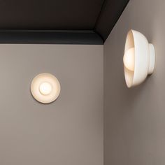 two light fixtures mounted on the wall next to each other in a room with gray walls