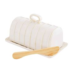 a wooden spatula next to a white cake on top of a plate with stripes