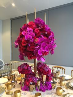 the centerpiece is adorned with purple and red flowers, gold candlesticks, and silver dishes