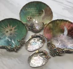 four seashells with pictures on them sitting on a marble counter top next to each other