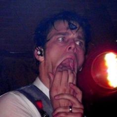 a man with his hands on his mouth in front of a red light