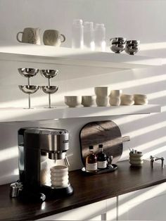 a coffee maker and cups on a shelf