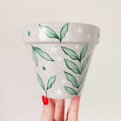 a woman's hand holding up a green and white planter with stars on it