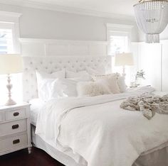 a white bed sitting in a bedroom on top of a wooden floor