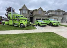 two green trucks parked in front of a house