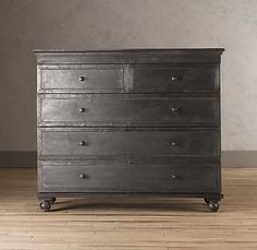 an old chest of drawers on a wooden floor with dark gray walls in the background