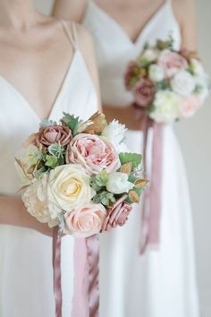 two bridesmaids in white dresses holding bouquets with pink and ivory flowers on them