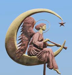 a statue of an angel sitting on the moon with a star in it's hand