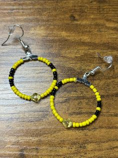 Medium sized hoop earrings with yellow and black beads. Made using glass Czech beads and bicone bead in the middle. Medium Hoop Earrings, Yellow And Black, Czech Beads, Delaware, Black Media, Black Beads, Yellow Black, In The Middle, Jewelry Earrings Dangle