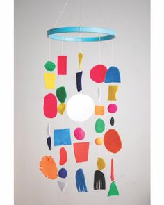 a colorful mobile hanging from a ceiling with circles and shapes painted on it's sides