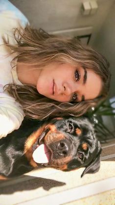 a woman laying on the ground next to a black and brown dog with it's tongue hanging out