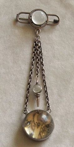 This is a rare example of a women's Chatelaine Watch pin. It is made of lower grade silver (less than 925 parts per 1000) and is not marked but has been tested., The brooch length is 5 1/2 inches from the top of the pin to the bottom of the ball watch. The top pin is 2 inches across and 9/16 inch at its widest. The ball watch is 1 1/8 inches across. The dial has some hairline cracks and is marked G.H. Oudin Palais Royal 52. The movement appears to be French as well. This watch is working and has its ball topped key for winding and setting. There are plenty of surface scratches on the glass balls, but no deep gouges, cracks or chips.C. 1860 and French. A true survivor! Follow me on instagram@jettesjewels. Antique Silver Brooch For Formal Occasions, Antique Silver Brooches For Formal Occasions, Formal Round Sterling Silver Brooches, Round Sterling Silver Brooches For Formal Occasions, Sterling Silver Round Brooches For Formal Occasions, Antique Silver Metal Brooch, Antique Silver Pendant Brooches, Victorian Formal Jewelry With Oxidized Finish, Formal Hallmarked Silver Brooches