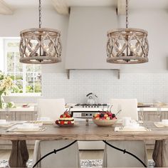 a kitchen table with two bowls of fruit on it and three lights hanging from the ceiling