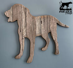 a wooden dog cutout hanging on the side of a wall in front of a gray background