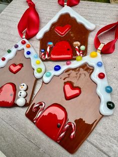 two gingerbread houses decorated with candy and candies are on a table next to a red ribbon