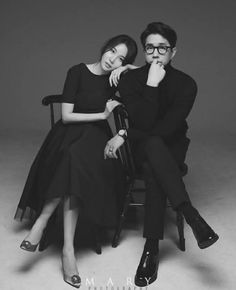 a man and woman sitting next to each other on a chair in front of a gray background